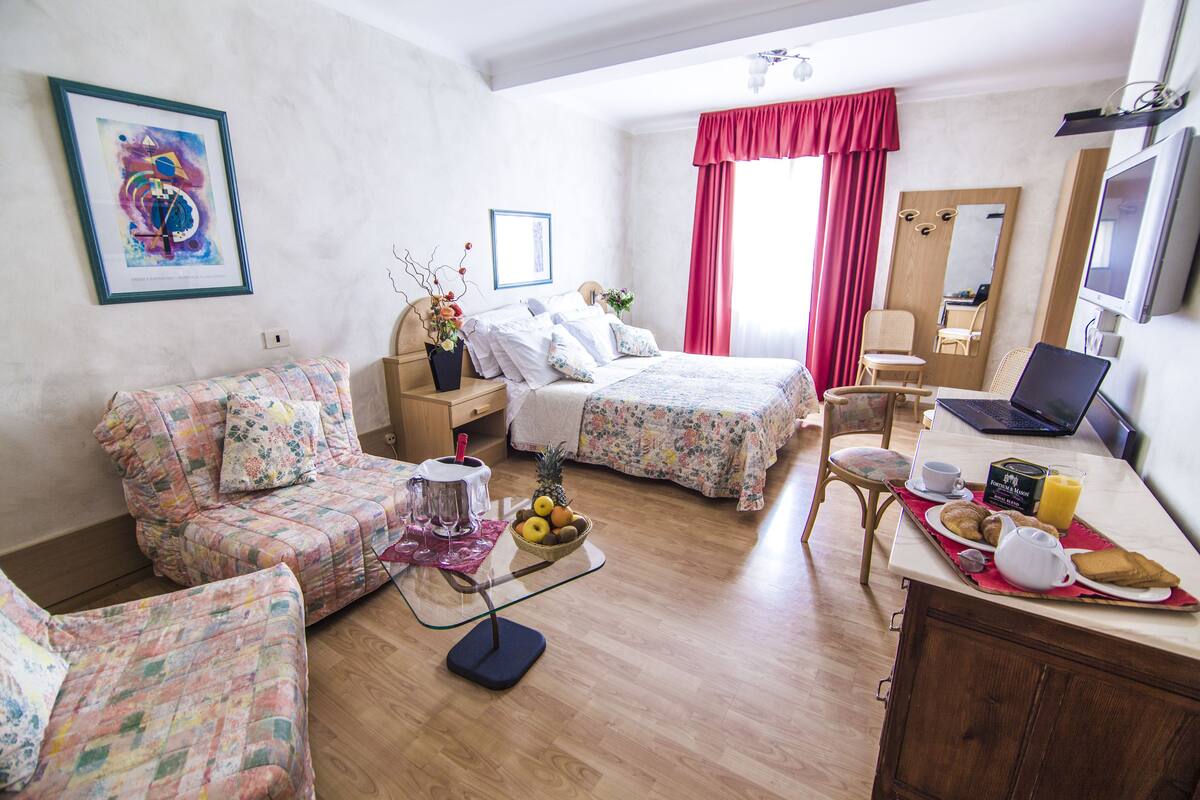 A hotel room with two beds, a desk with a laptop, a breakfast tray, and a mirror.