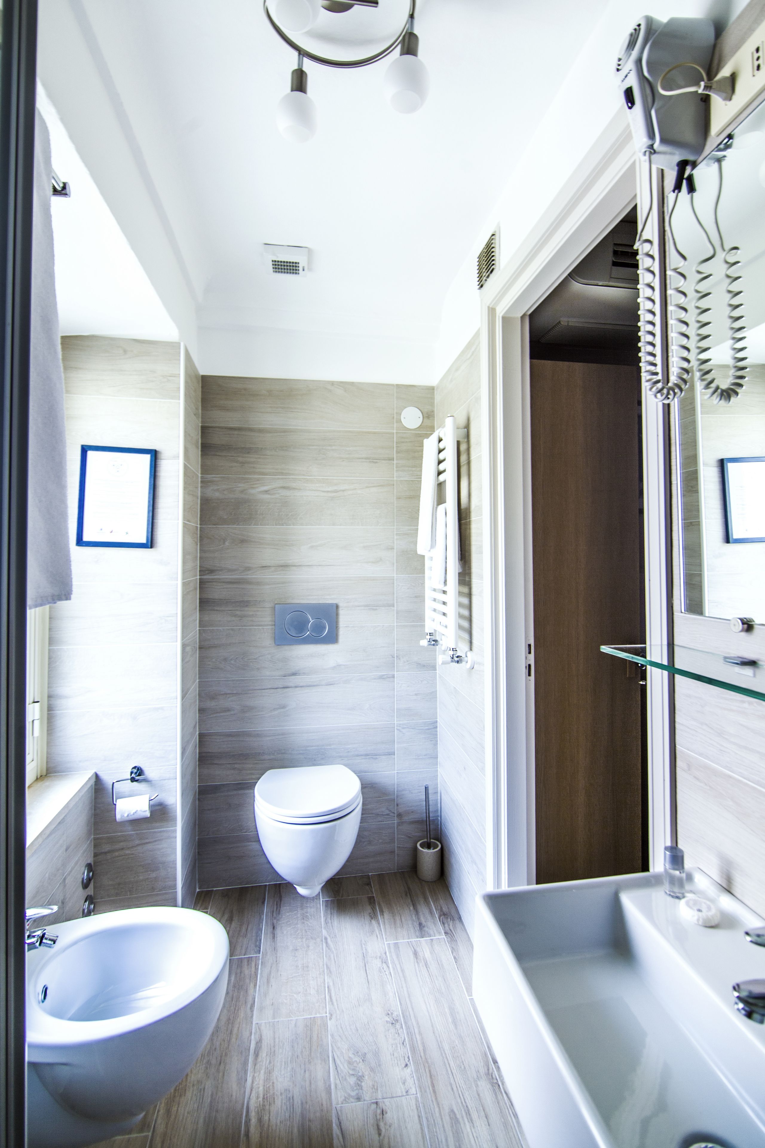 A modern bathroom with a bidet, toilet, and glass shower enclosure.