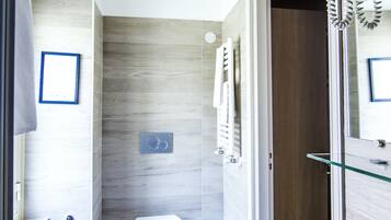 A modern bathroom with a bidet, toilet, and glass shower enclosure.