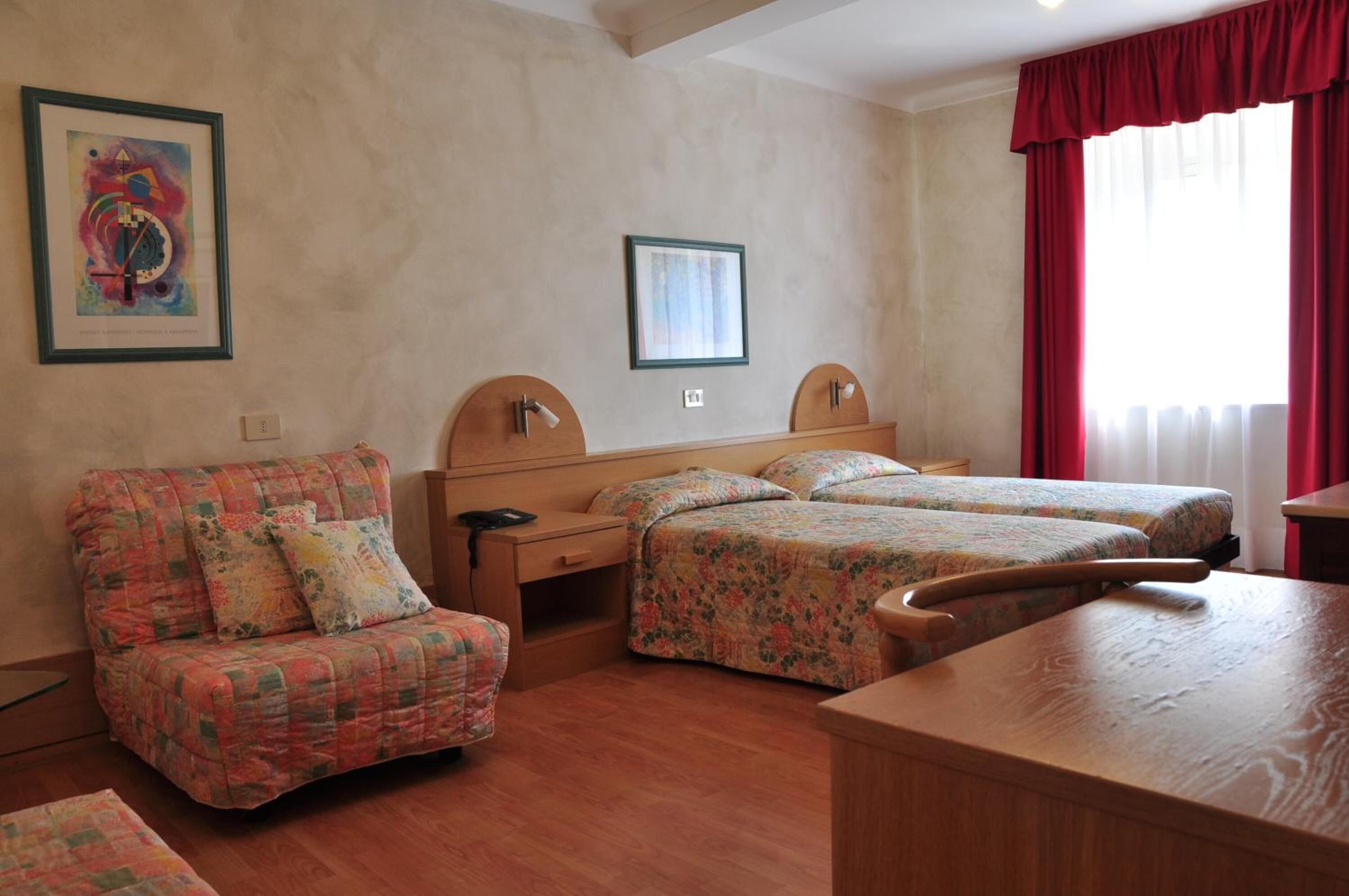 Ein Hotelzimmer mit Bett, Sofa, Schreibtisch und einem Fenster mit Vorhängen.