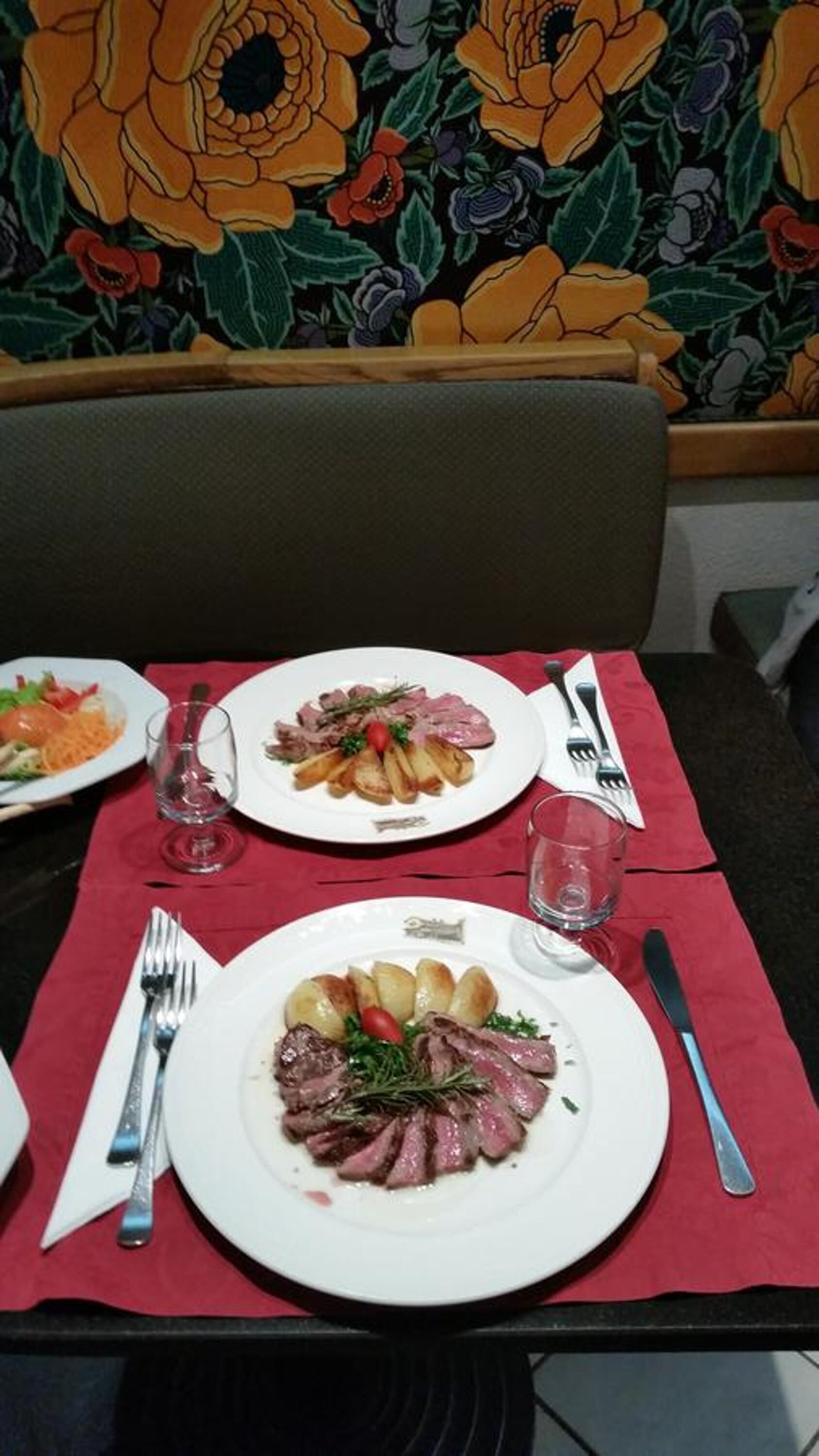 Una mesa de comedor con platos de comida, cubiertos y vasos.