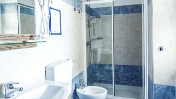 Une salle de bain avec douche, toilettes et lavabo.