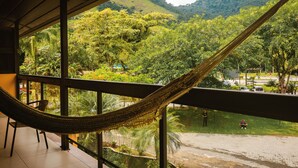 Una hamaca en un balcón con vistas a un paisaje verde exuberante y una montaña al fondo.