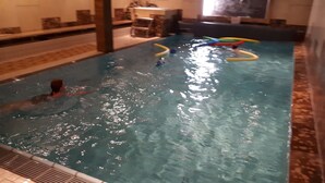 Une piscine intérieure à l’eau claire, un nageur et des jouets de piscine aux couleurs vives.
