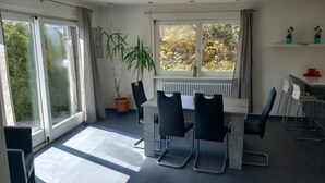 Un espace repas moderne avec une grande fenêtre, une plante en pot et une table avec des chaises.