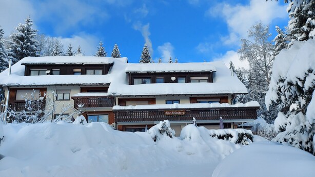 Un hôtel à l’architecture de style chalet traditionnel, doté de nombreux balcons et d’une enseigne indiquant qu’il s’agit d’un établissement accueillant les familles.