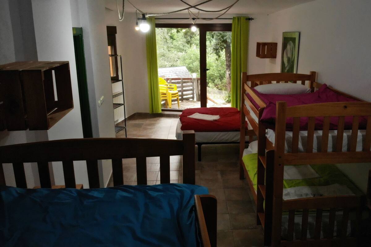 Ein Schlafsaalzimmer mit Etagenbetten, einem kleinen Tisch und einem Fenster mit Vorhängen.