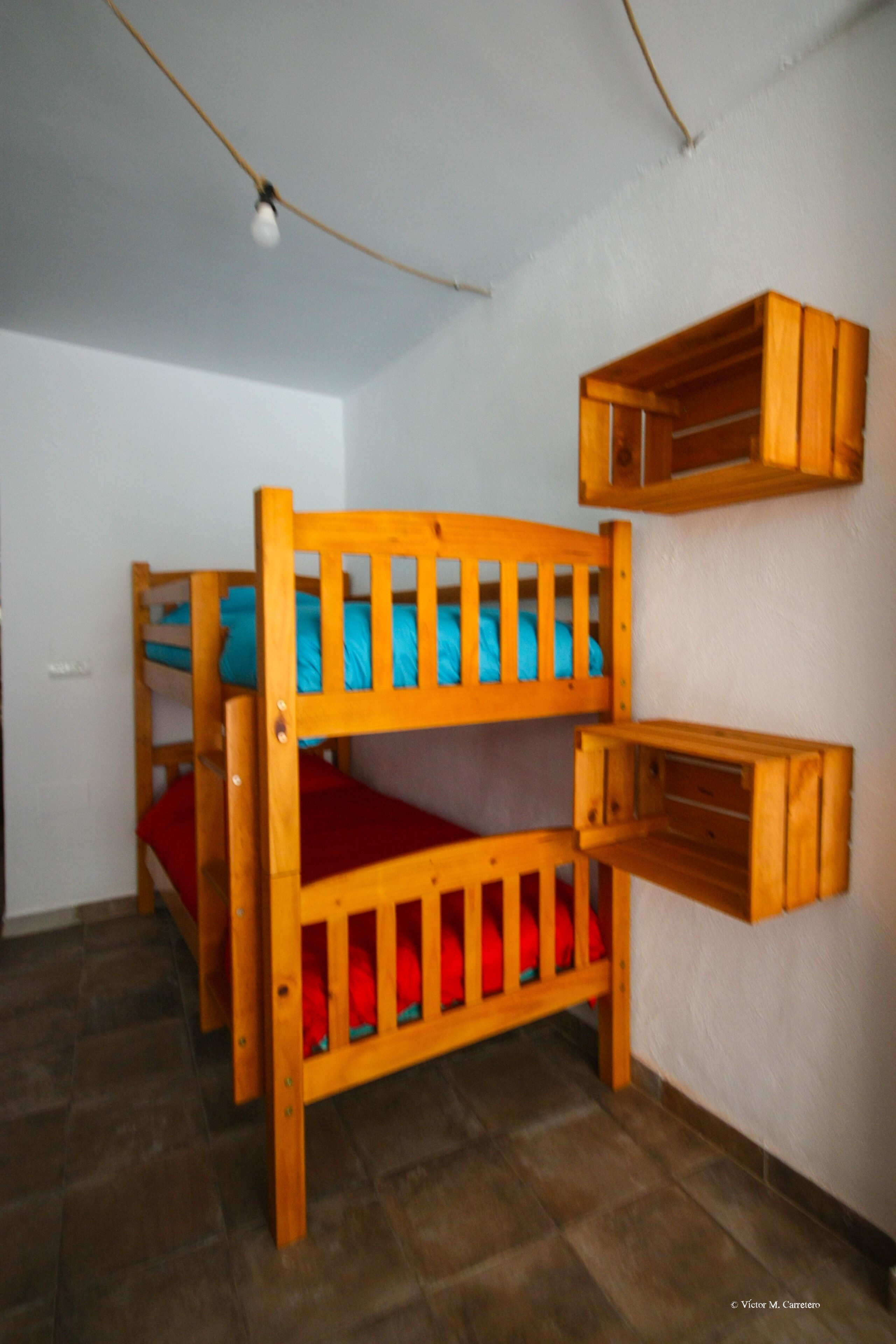 A bunk bed with a red mattress and a wooden headboard.