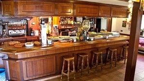 Un espace bar avec des meubles de rangement en bois, une machine à café et un assortiment de collations et de boissons.