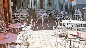 An outdoor patio with white metal tables and chairs, arranged in rows.