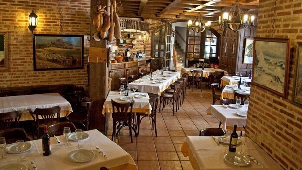 Un restaurant aux murs de briques, aux poutres apparentes et aux tables dressées pour le service.