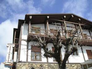 A two-story building with a sign indicating a hostel and restaurant. - Hostal La Maya (Cercedilla)