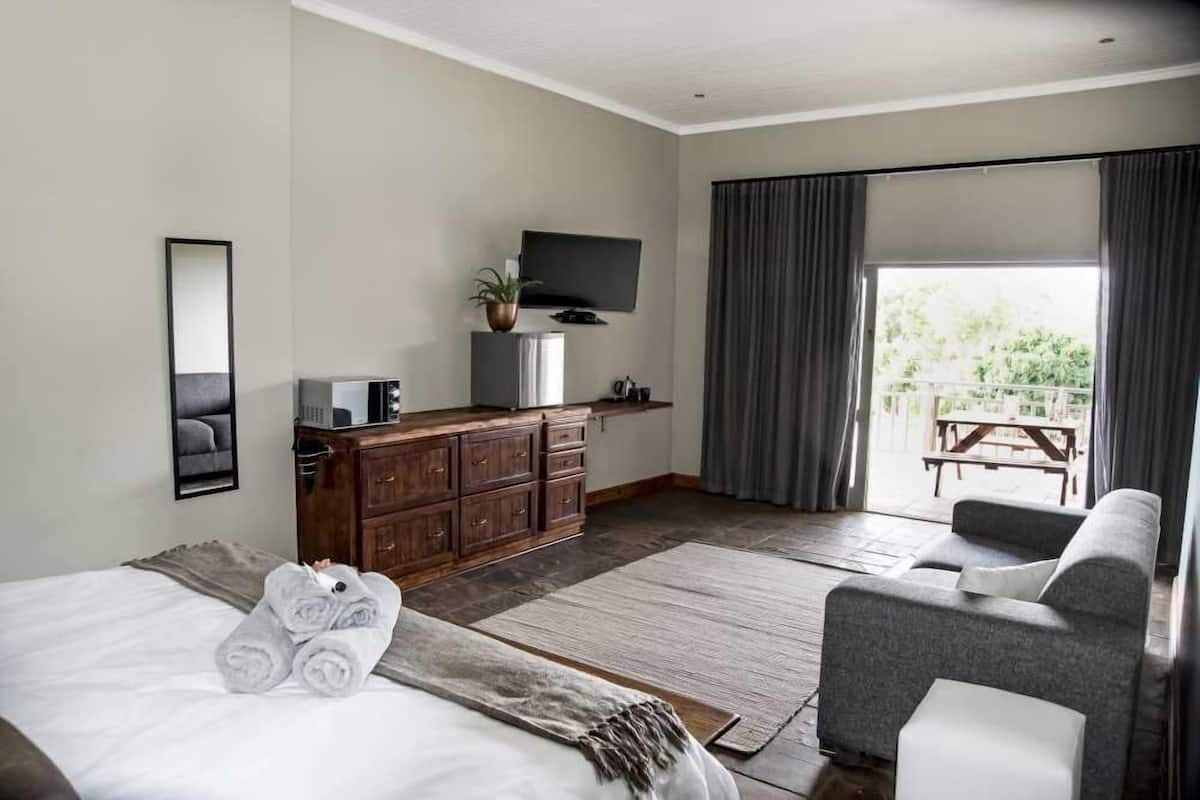 Ett modernt hotellrum med en säng, en soffa, en TV, en byrå och en balkong med gardiner.