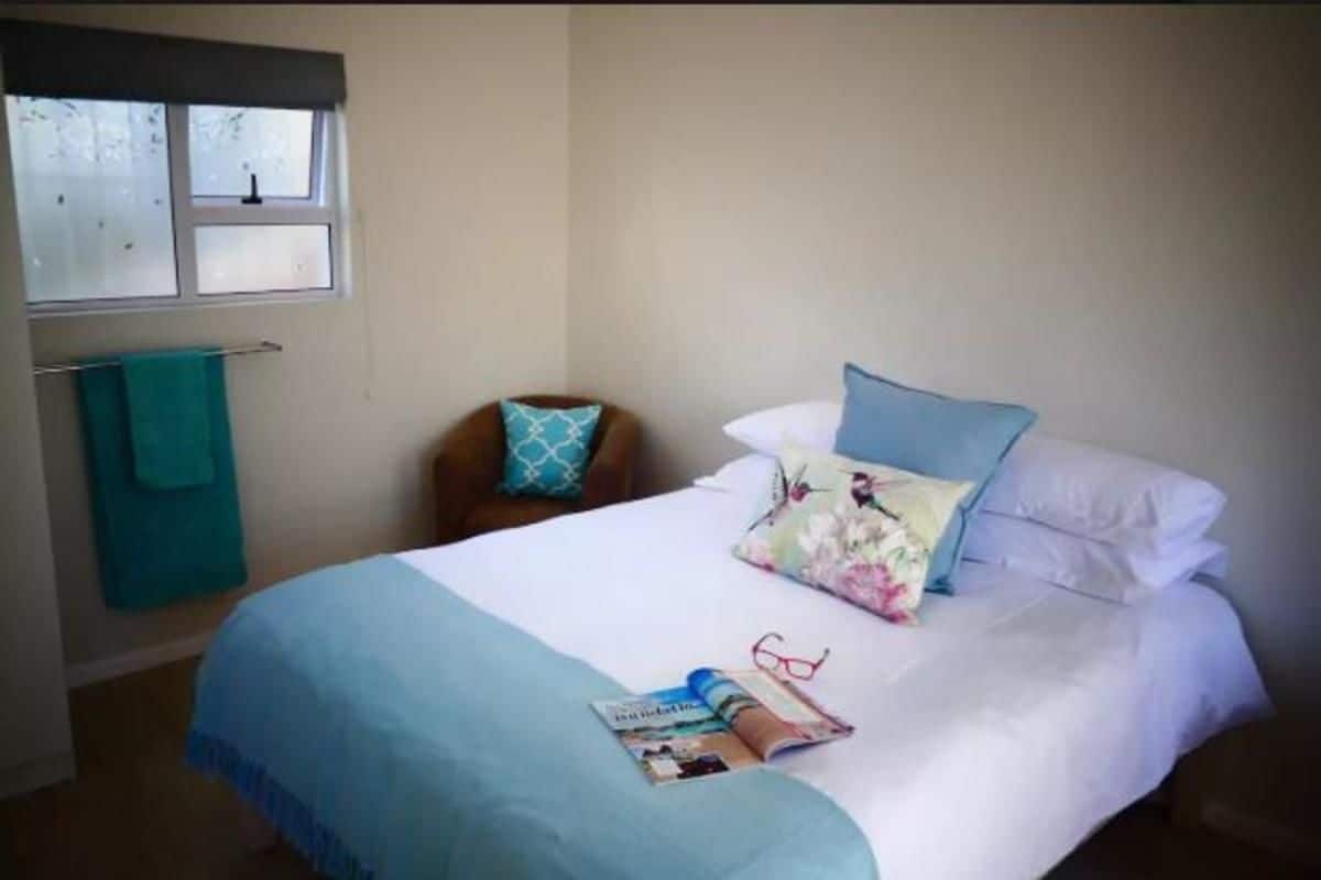 A bedroom with a bed, a window, a chair, and a towel rack.