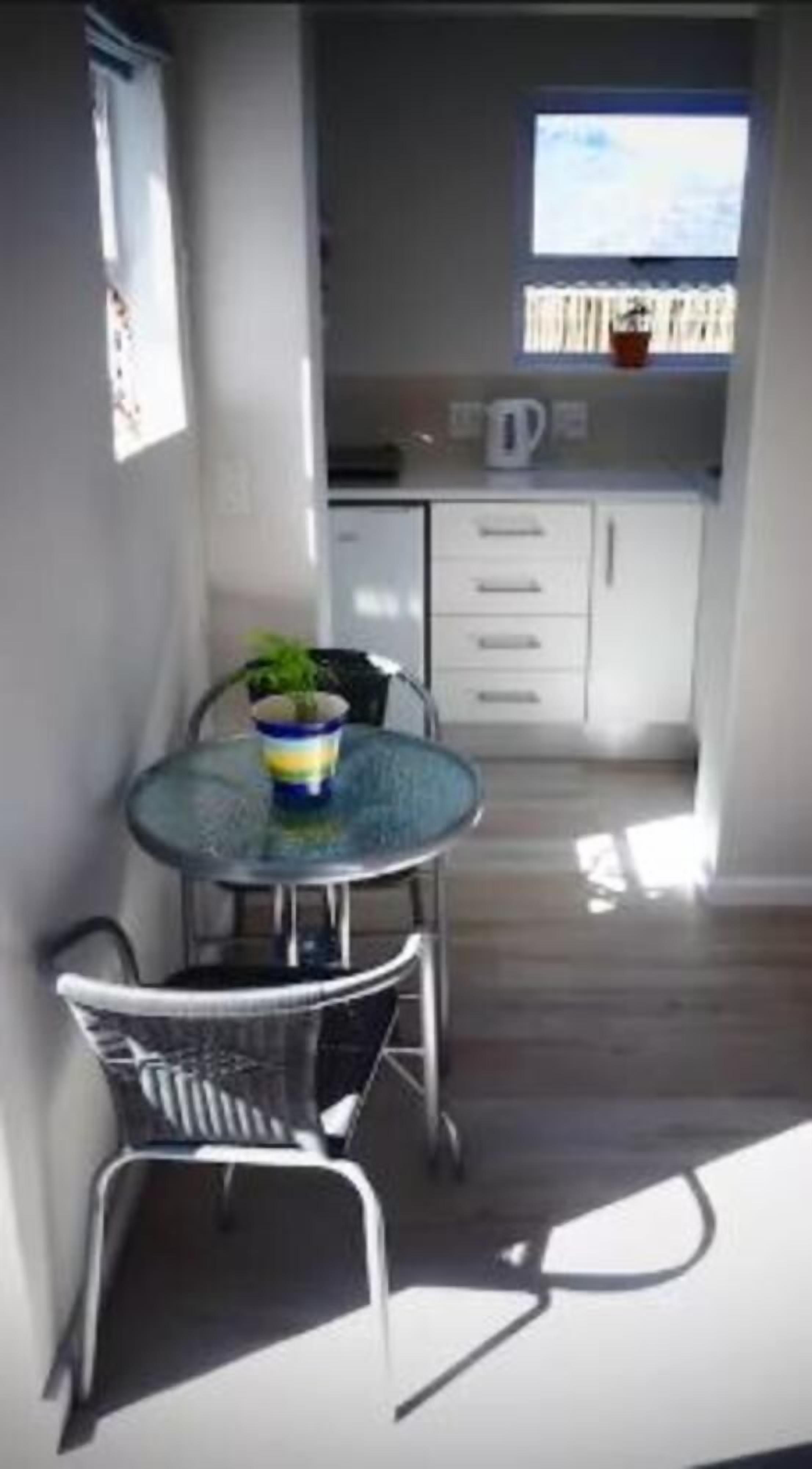 A small dining area with a table and chairs, a potted plant, and a window with a view.