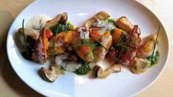 A white plate with a dish of roasted vegetables and herbs.
