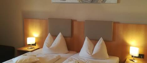 A hotel room with a double bed, two bedside tables with lamps, and a modern abstract painting on the wall.