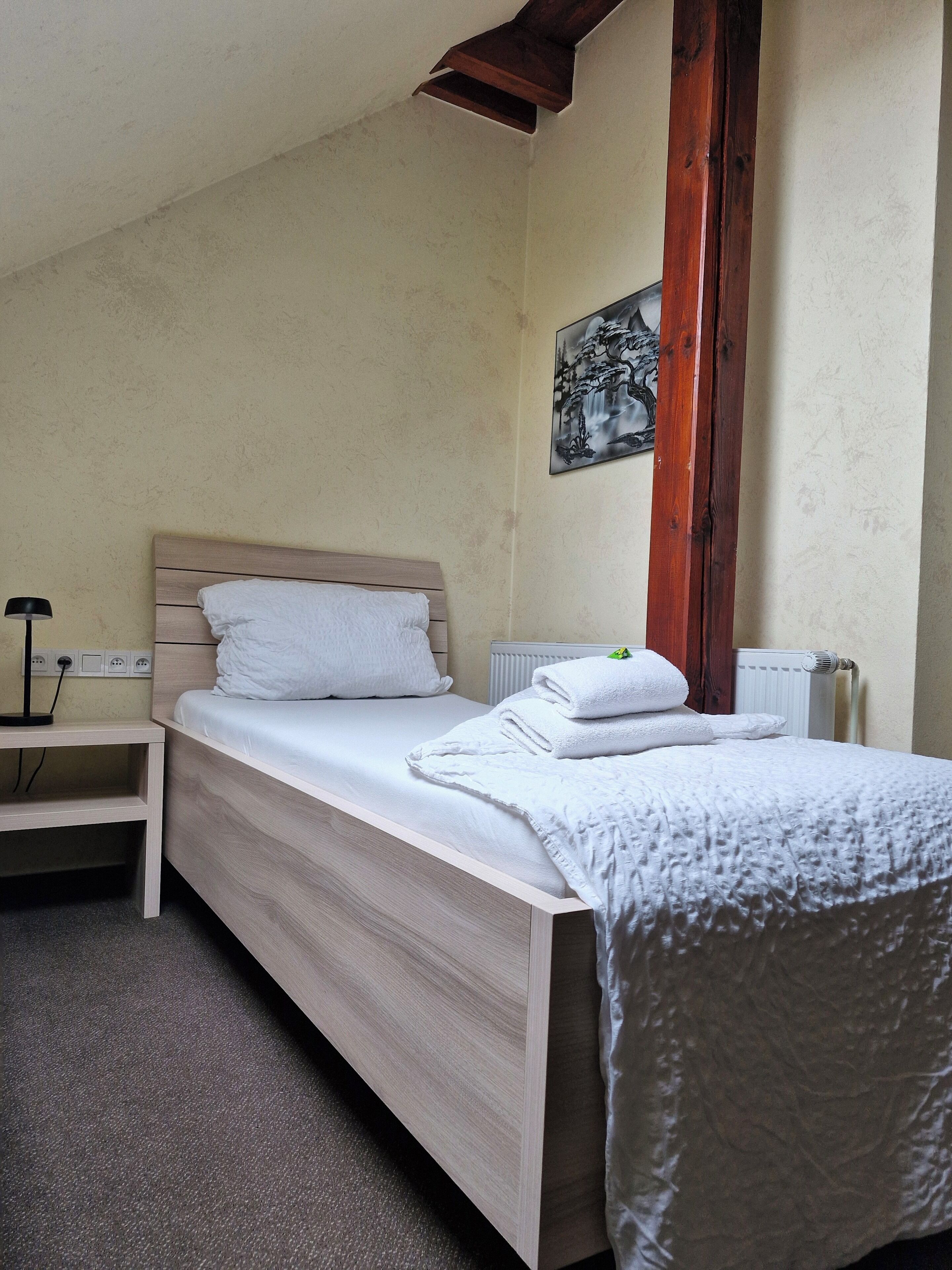 Una cama individual con cabecera de madera, una mesita de noche y un radiador.