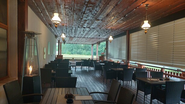 A restaurant with wooden tables and chairs, a fire feature, and large windows with blinds. - Penzion Country Steak Restaurant (Albrechtice)