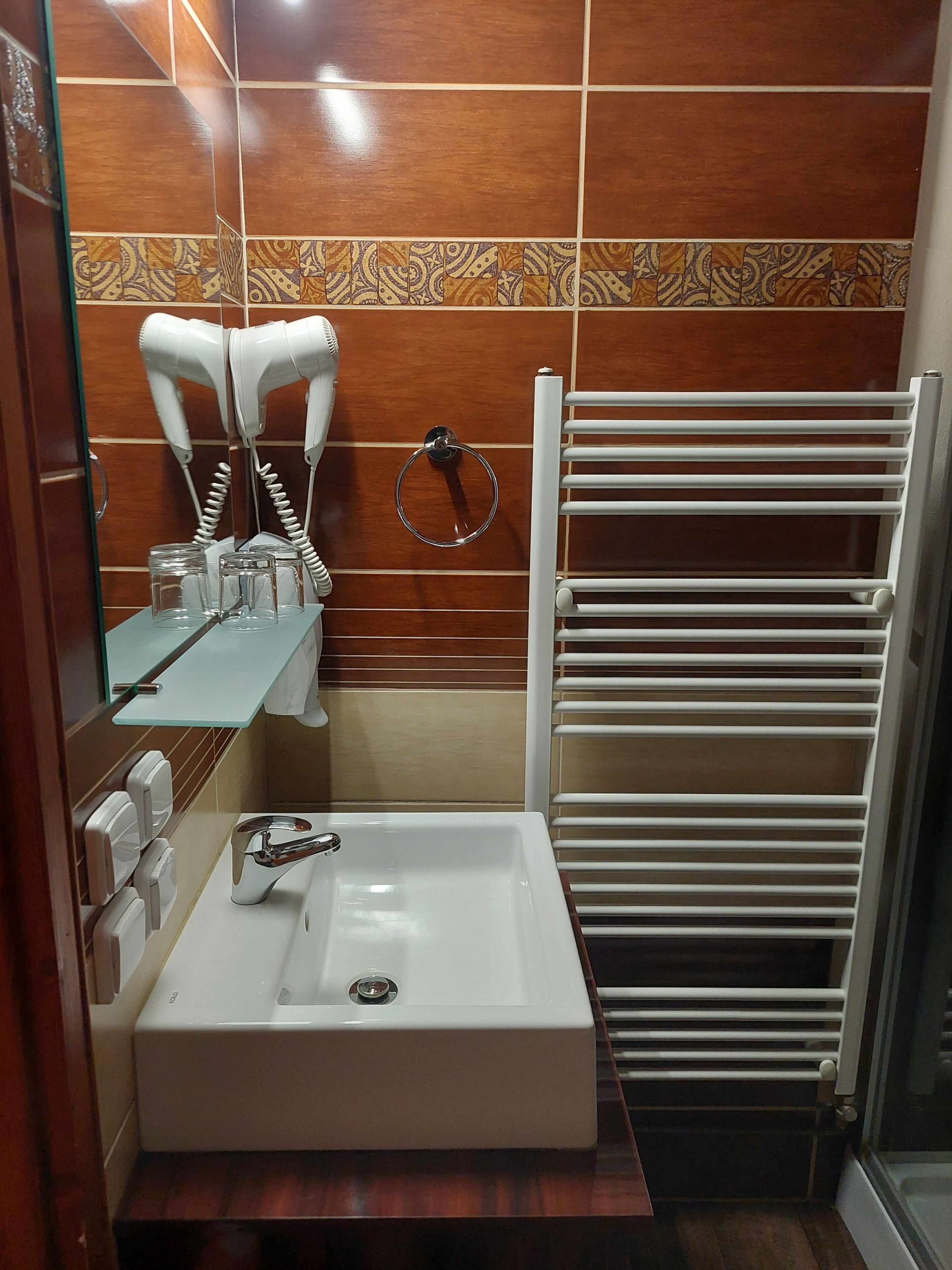 Un baño con un lavamanos blanco, un perchero y un secador de pelo.