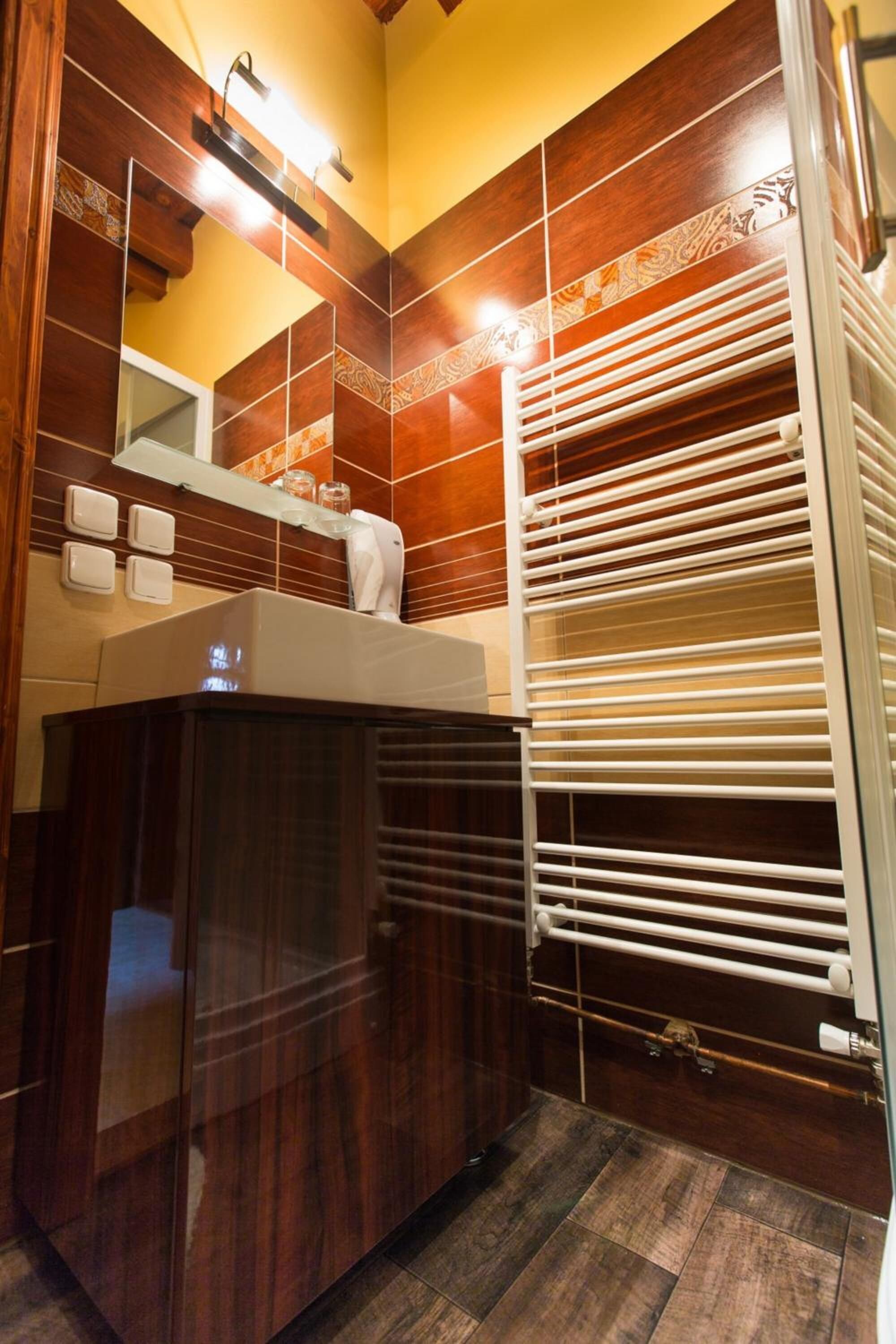 Een badkamer met een houten wastafelmeubel, een spiegel en een handdoekhouder.