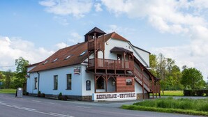 A building with a white facade, wooden balcony, and a sign that reads "RESTAURACE - UBYTOVÁNÍ". - Penzion Country Steak Restaurant (Albrechtice)