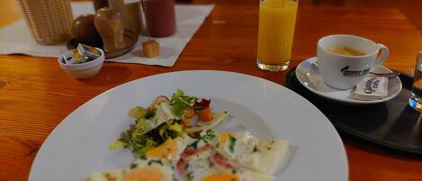Un desayuno con un plato de huevos, un vaso de jugo de naranja y una taza de café sobre una mesa de madera.