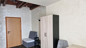 A room with a wooden door, a grey chair, a wardrobe, and a small table. - Penzion Country Steak Restaurant (Albrechtice)