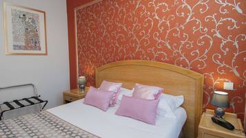 A neatly made bed with a wooden headboard, two bedside tables with lamps, and a patterned wall.