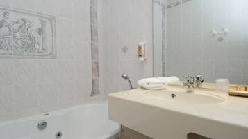 A bathroom with a bathtub, a sink, and a mirror.