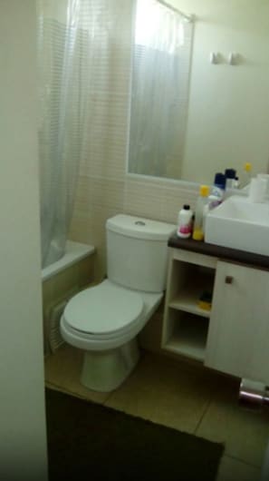 A small bathroom with a toilet, a sink, and a shower curtain. - 56.- HNA Capri (La Serena)