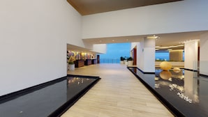 Un moderno vestíbulo de hotel con suelo de madera, una recepción y vistas al mar.