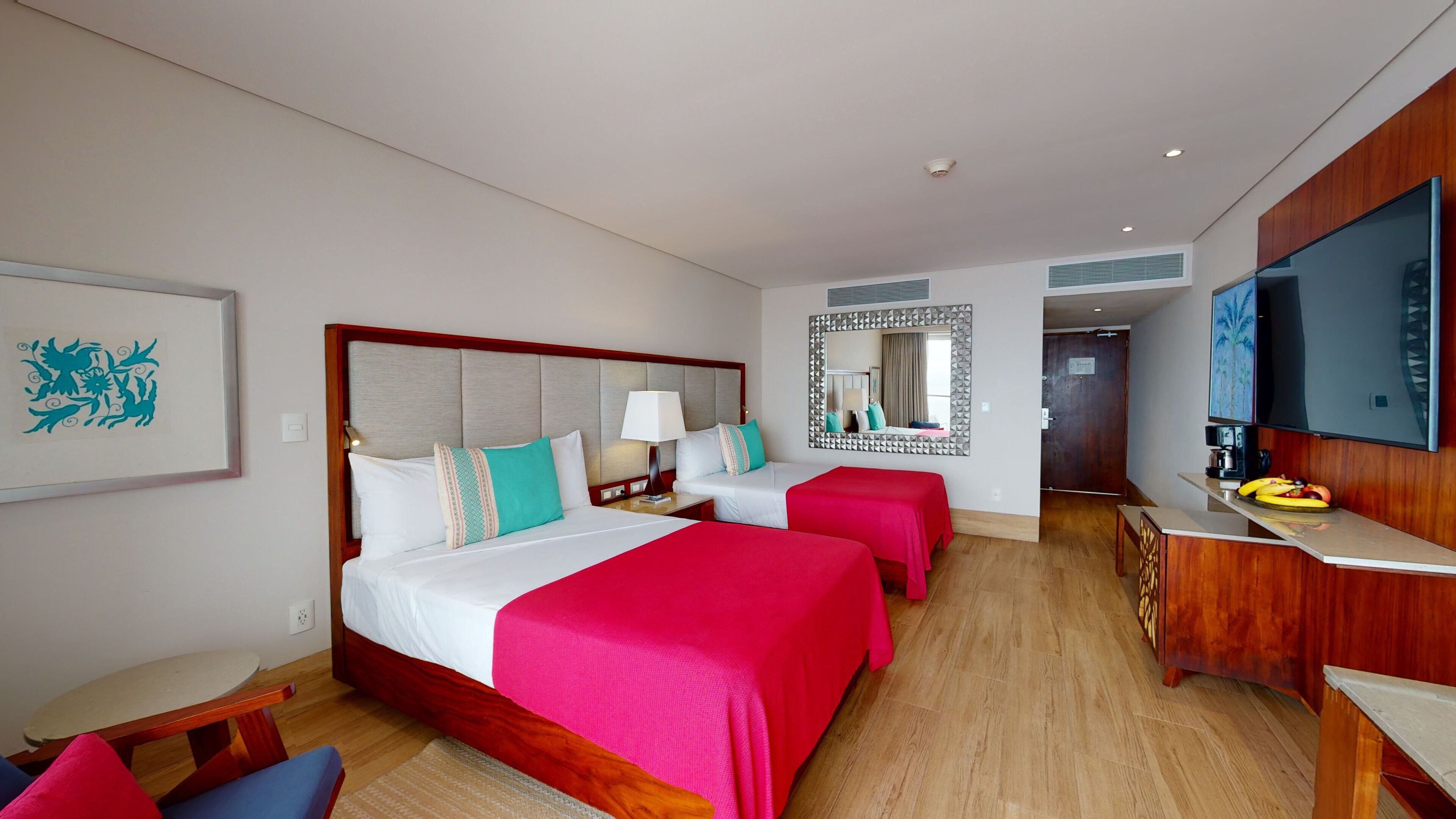 Una habitación de hotel con dos camas, televisión, escritorio y espejo.