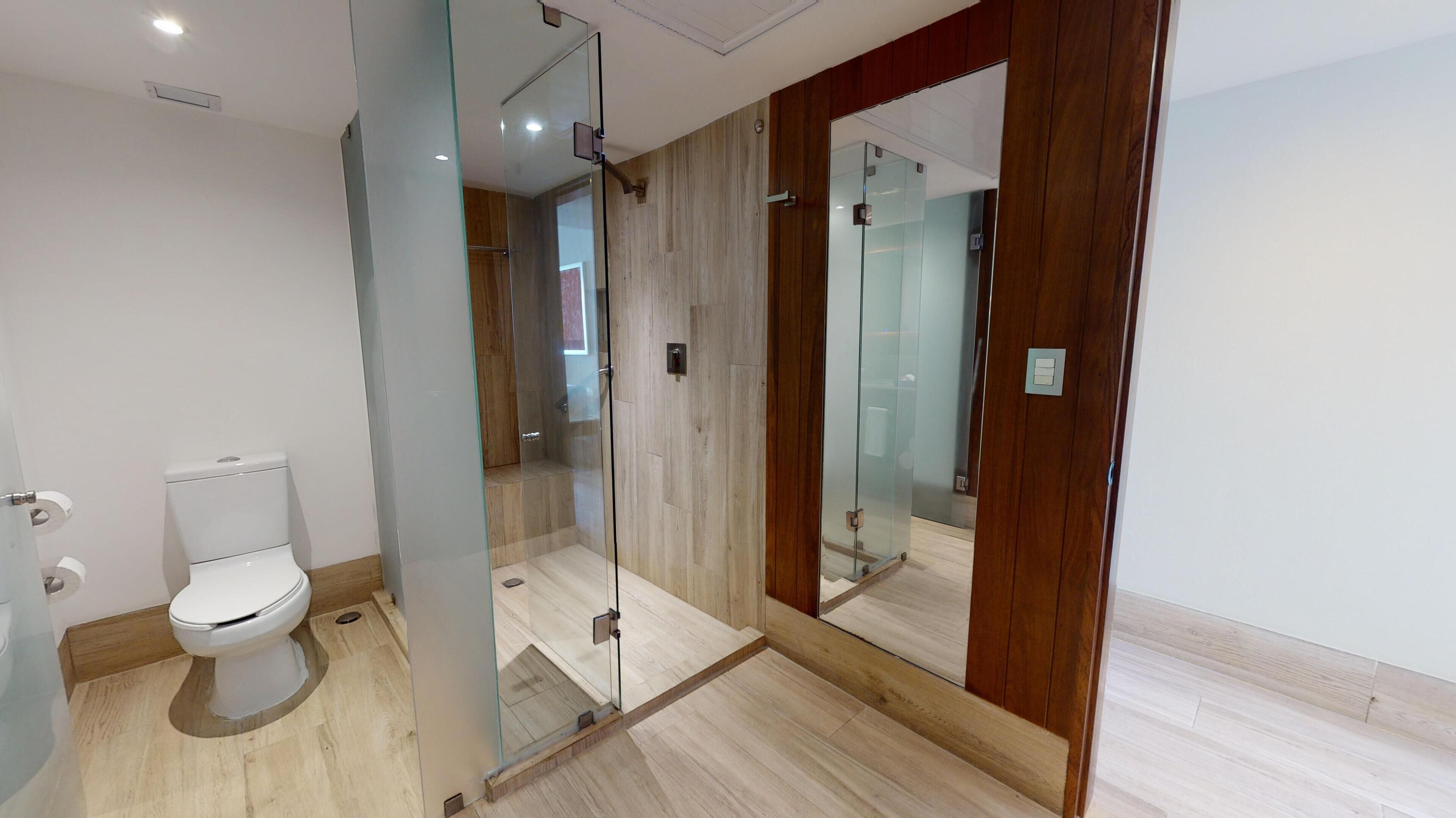 Ein modernes Badezimmer mit Duschkabine aus Glas, Toilette und Holzwaschbecken.