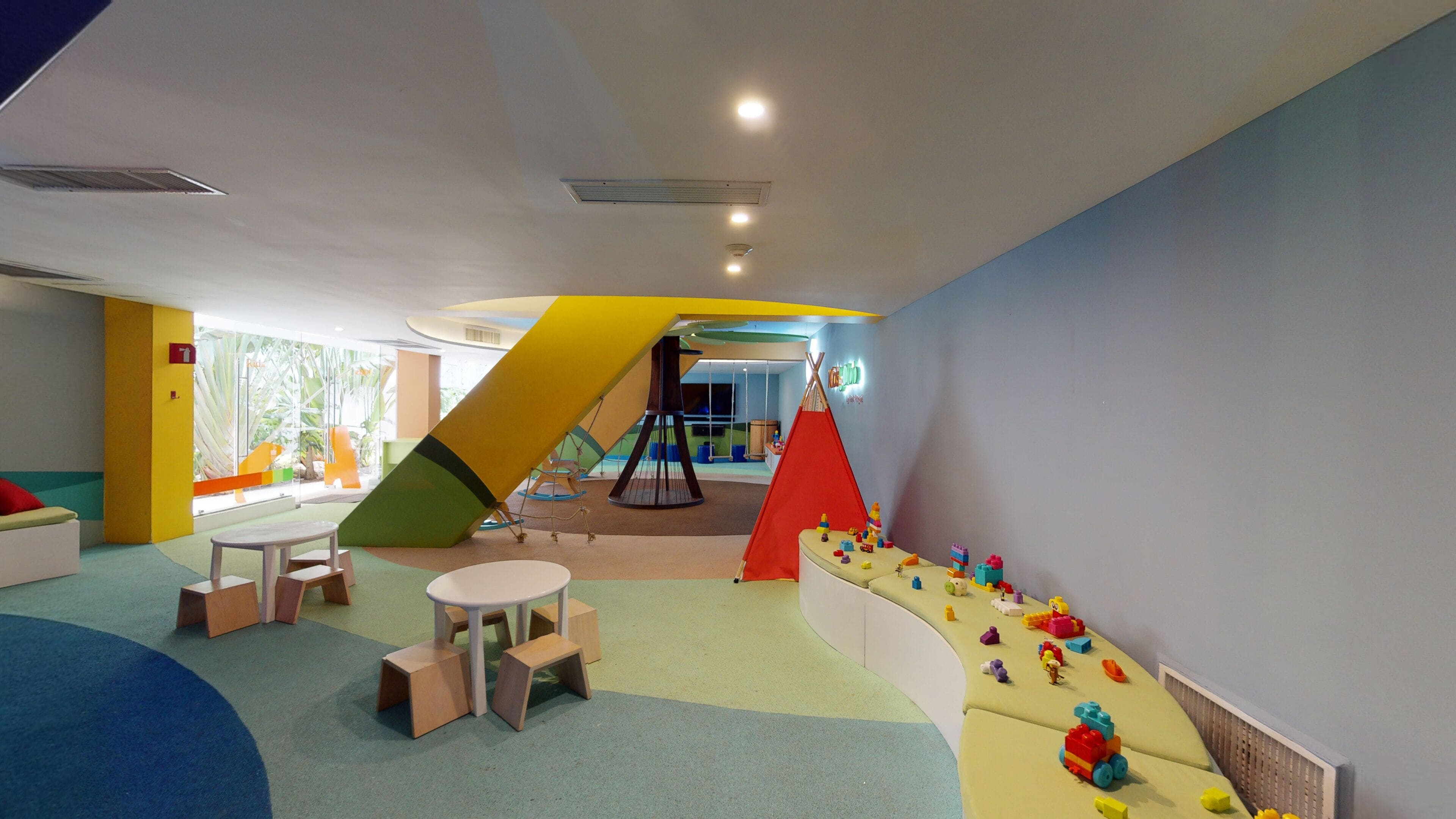 A children's play area with a slide, climbing wall, and soft play surfaces.