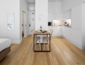 Une cuisine moderne avec des meubles blancs, une table à manger en bois et un four à micro-ondes.