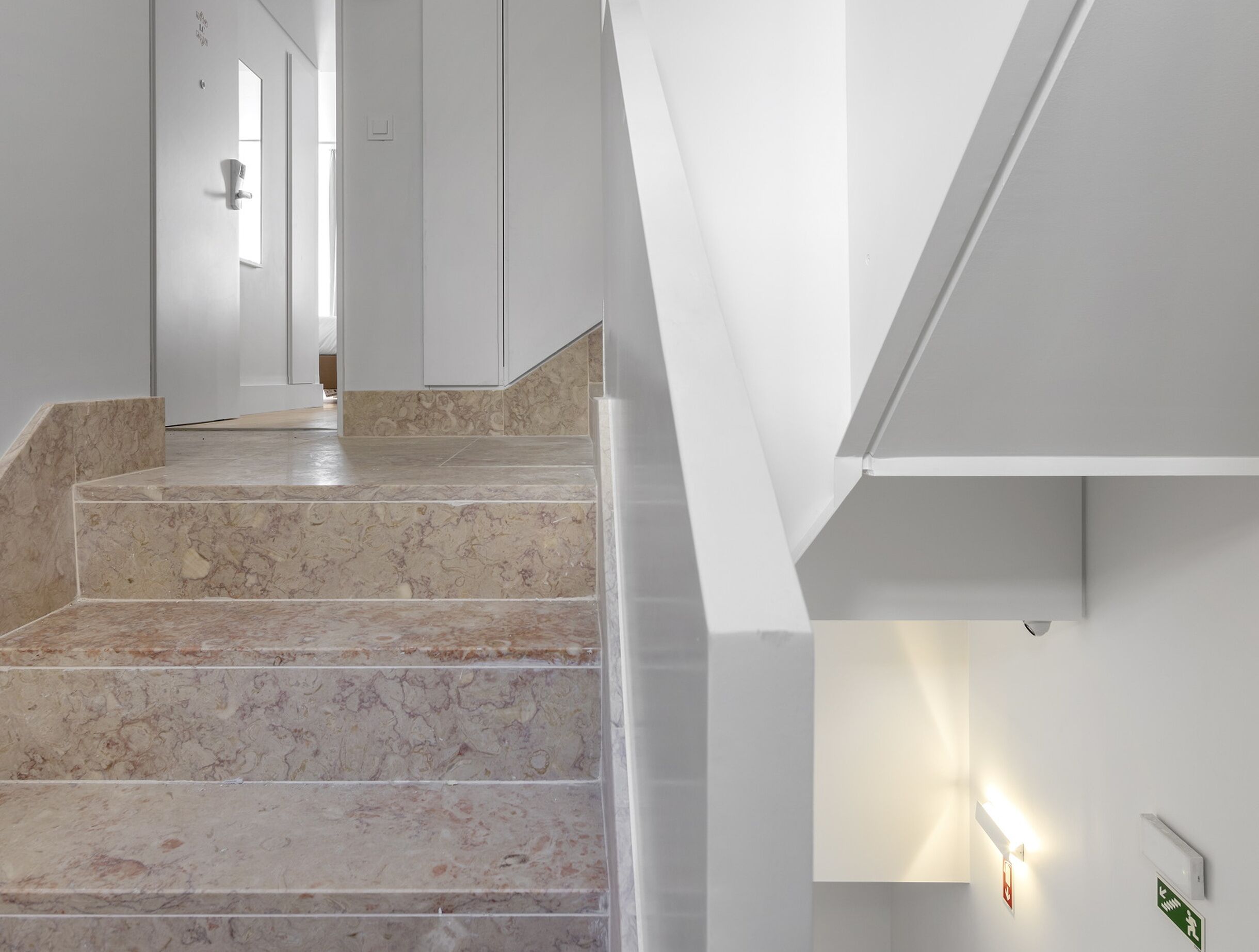 Ein modernes Interieur mit einer Marmortreppe, weißen Wänden und einer Leuchte.