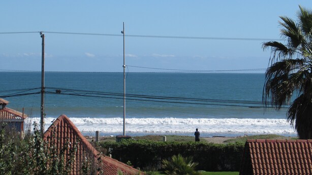 A coastal view with a clear sky, a beach, and a person standing by the water. - 61.- HNA Reinos Italia (La Serena)