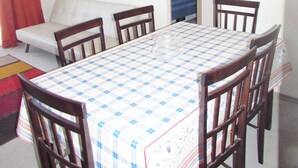 A dining area with a checkered table, wooden chairs, a sofa, and a painting on the wall. - 61.- HNA Reinos Italia (La Serena)
