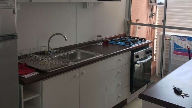 A modern kitchen with white cabinets, a stainless steel sink, and a built-in oven. - 51.- HNA Reinos Celta (La Serena)