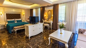 A hotel room with a large bed, a TV, a desk, and a coffee table. - Flora Uzungol Resort Hotel (Çaykara)