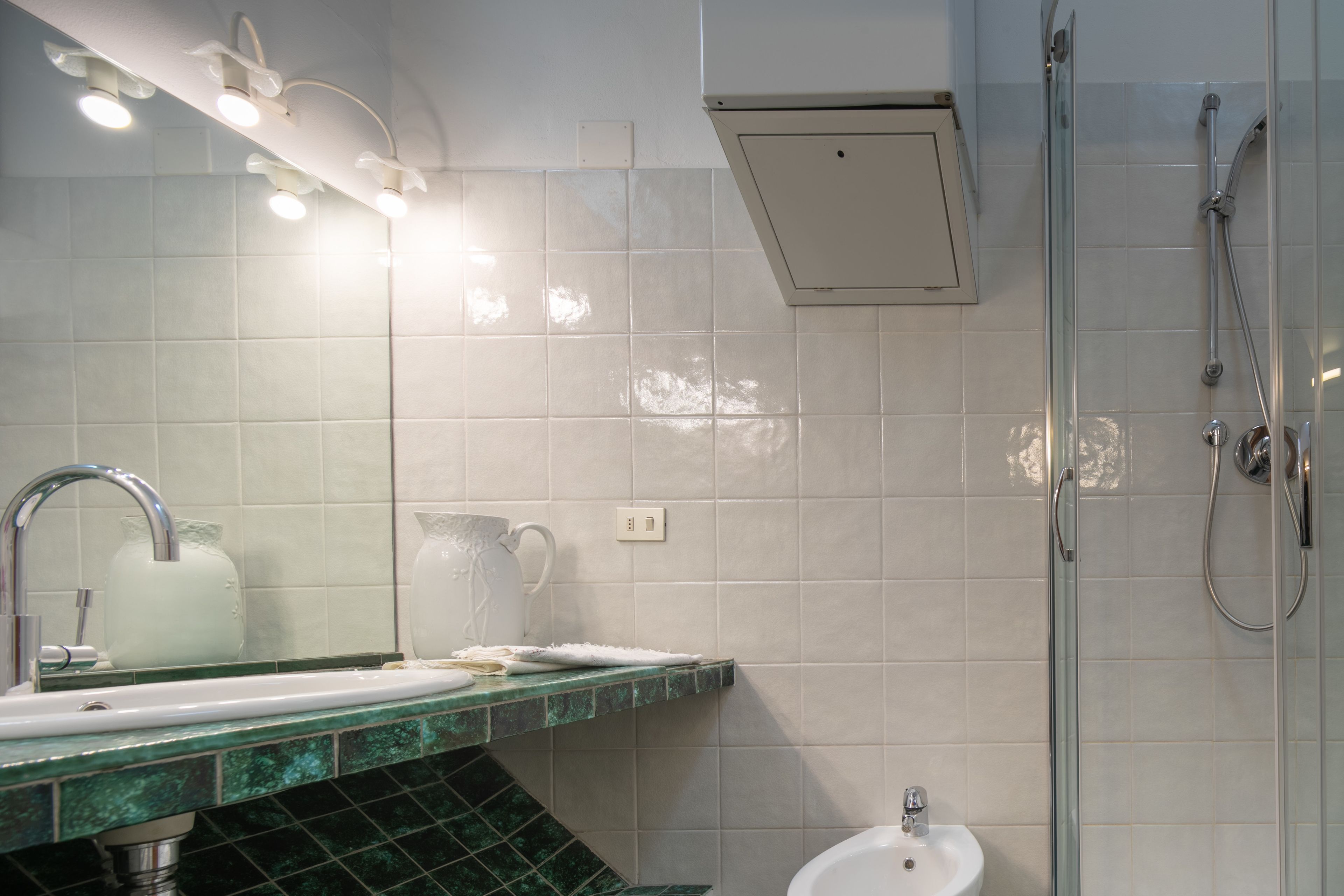 Un baño con lavamanos, espejo, ducha y lámpara.
