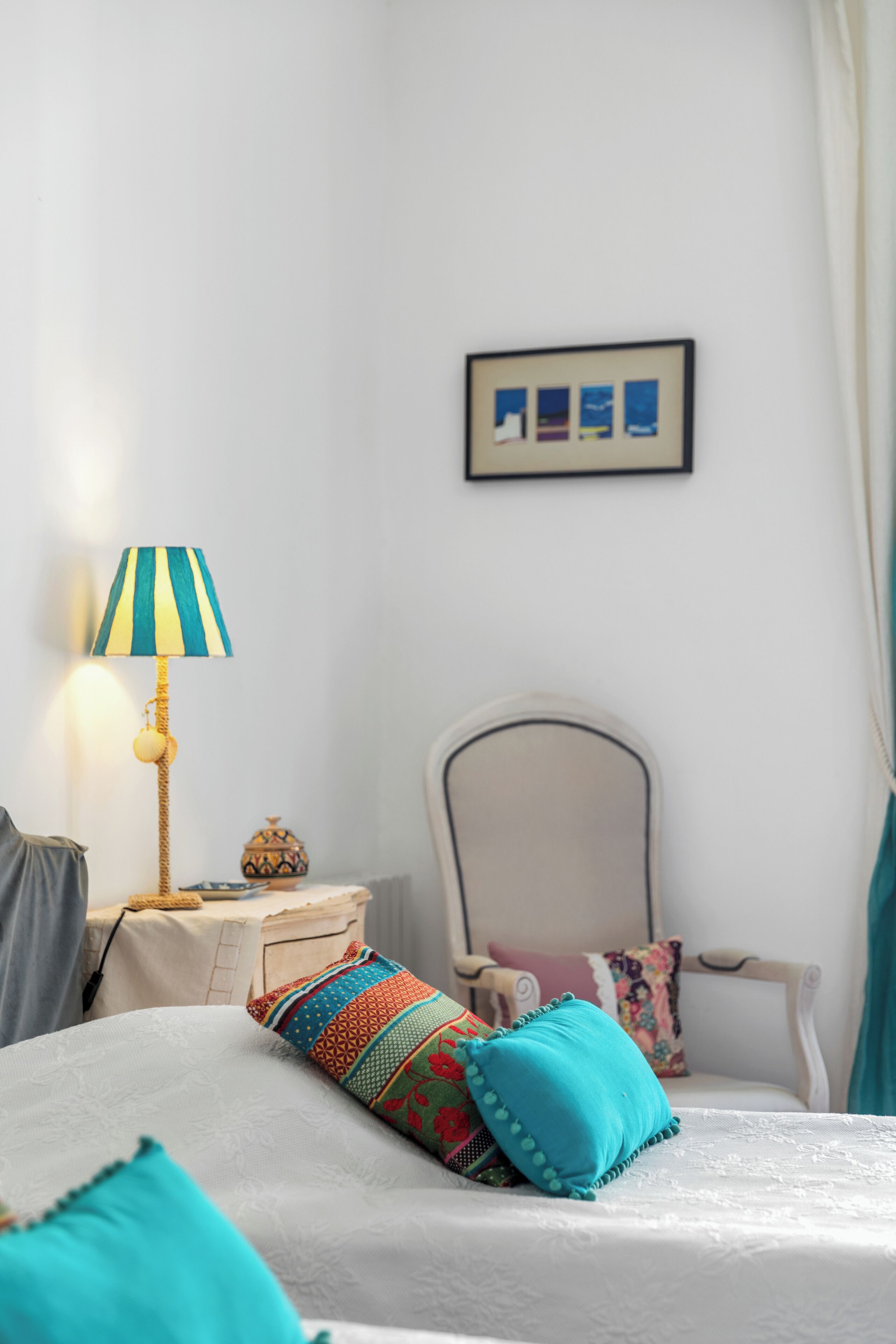 A neatly arranged bedroom with a bed, a bedside lamp, a chair, and a small table with a decorative item.