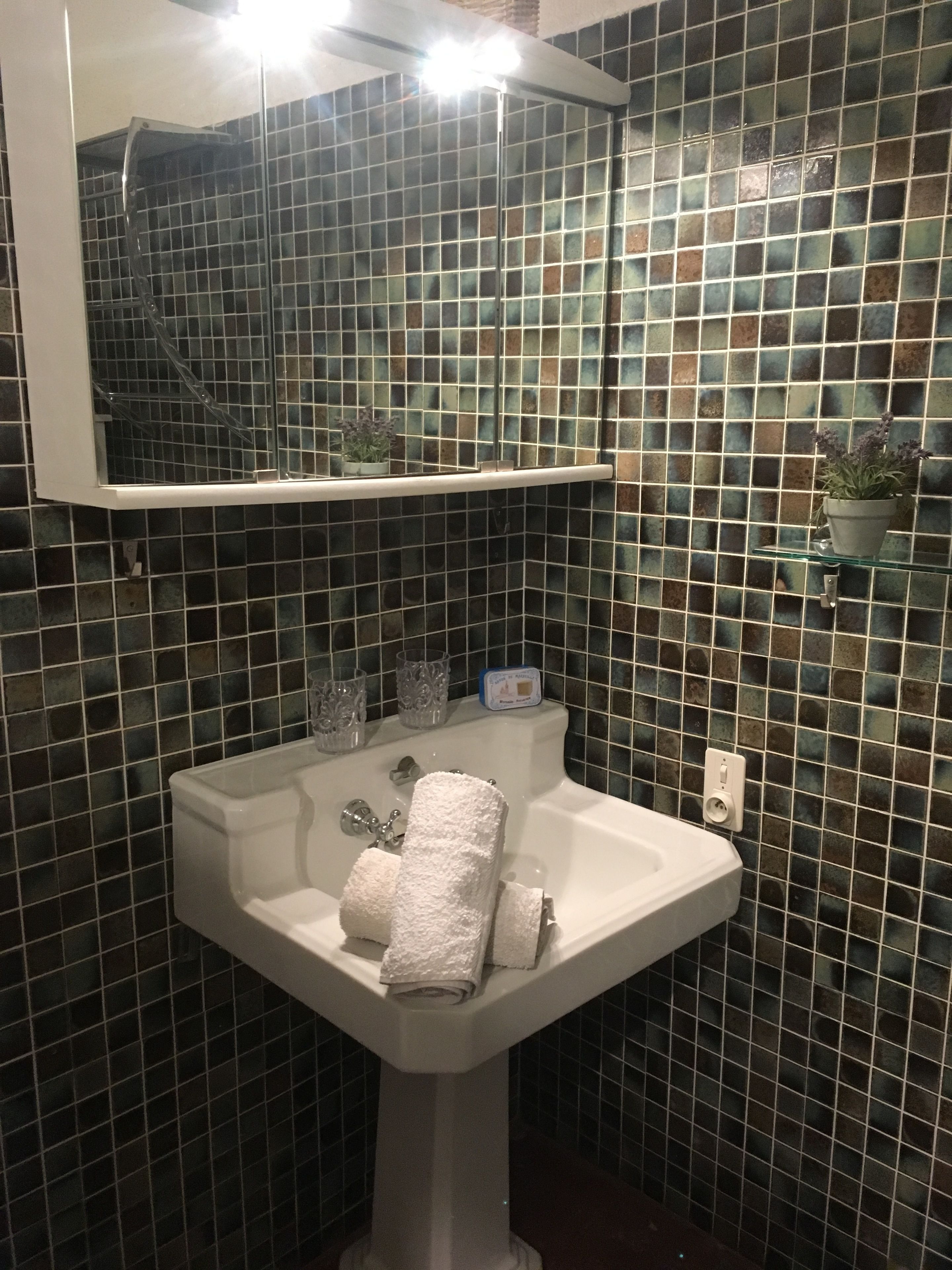 A bathroom with a white sink, a mirror above it, and a tiled wall.