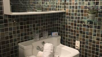 A bathroom with a white sink, a mirror above it, and a tiled wall.