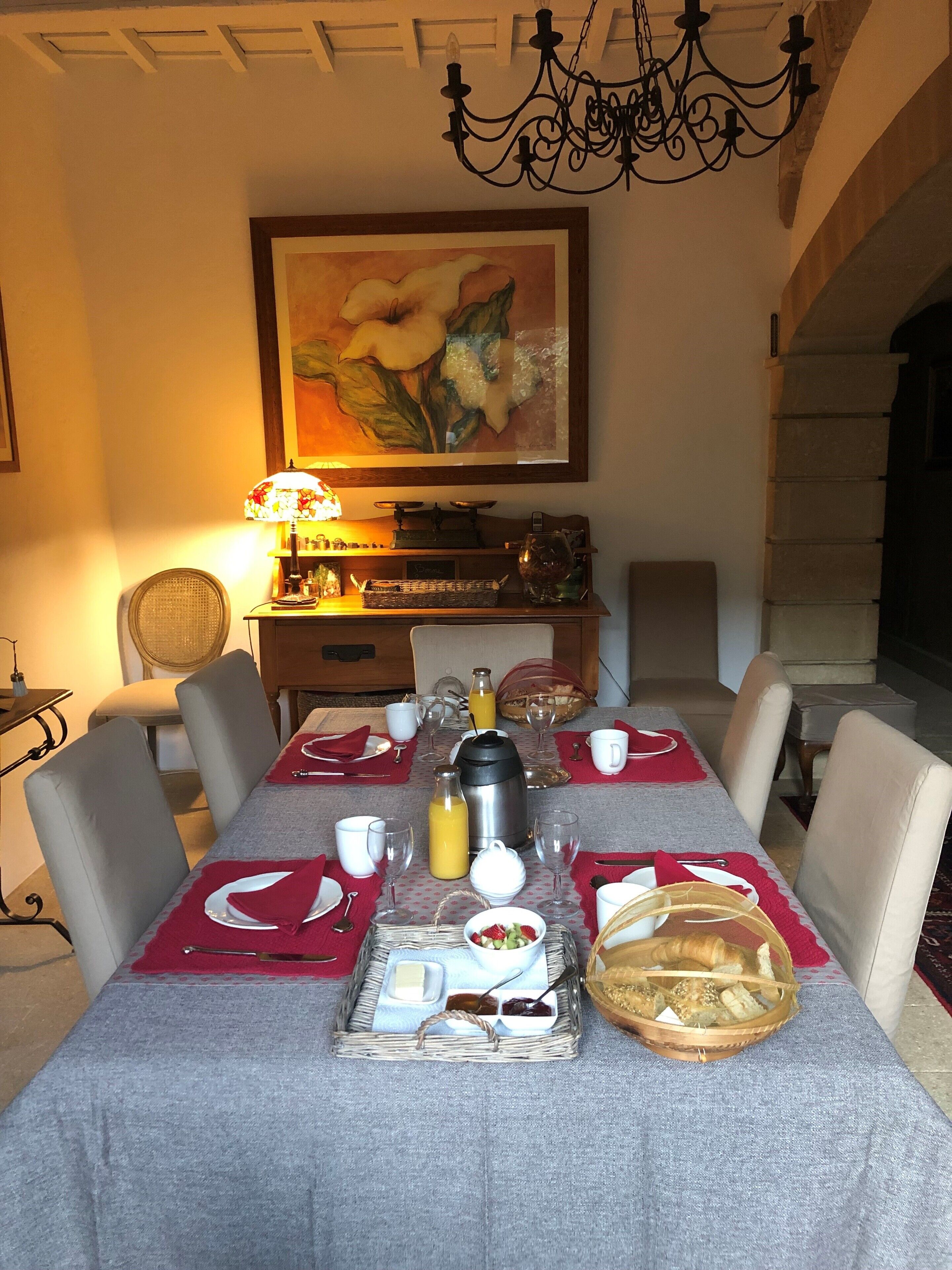 A dining area with a table set for breakfast, including bread, butter, jam, and a coffee pot.