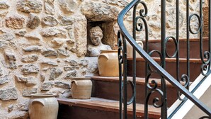 Un mur de pierre orné d’une statue et de poteries disposées sur des marches.