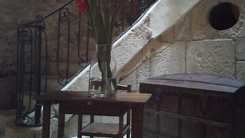 A stone staircase with a metal railing, a wooden table with a vase of flowers, and a stone wall with a circular cutout.