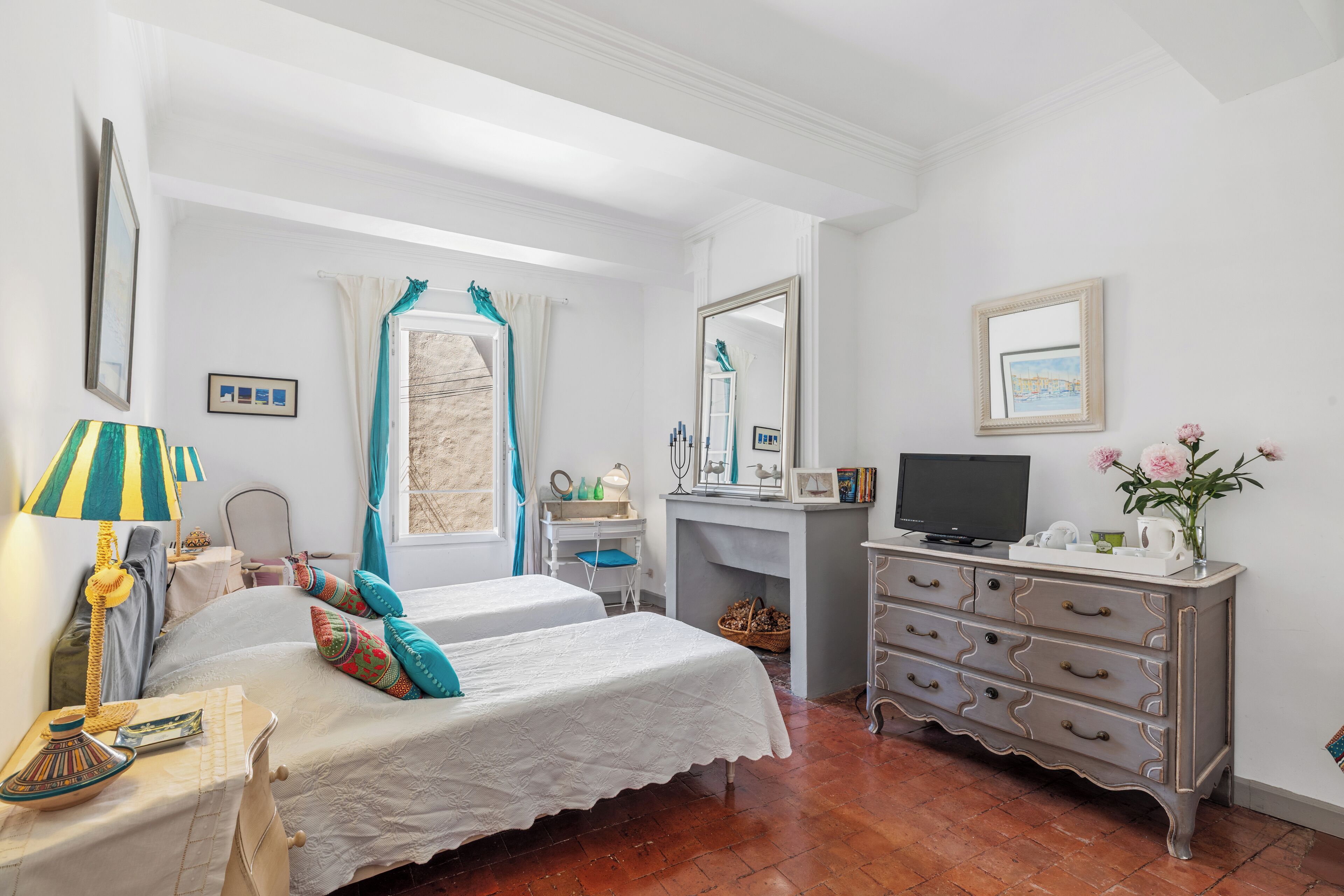A bedroom with two beds, a desk, a dresser, and a television.