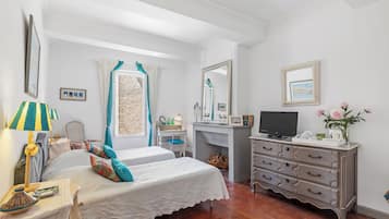 Une chambre avec deux lits, un bureau, une commode et un téléviseur.